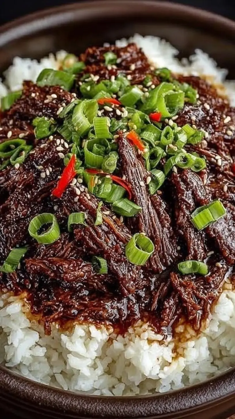 Close-up of slow cooker Korean beef served over fluffy white rice, topped with sliced green onions, sesame seeds, and thin red chili strips.