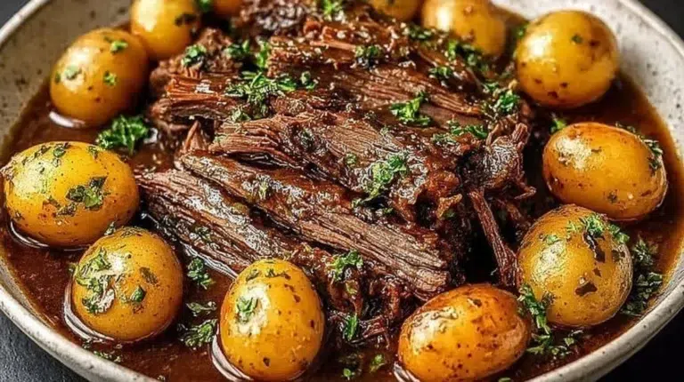 Delicious crock pot pot roast meal served with vegetables and herbs.