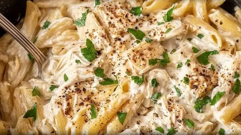 Creamy Crockpot Chicken Alfredo with pasta and herbs in a bowl.