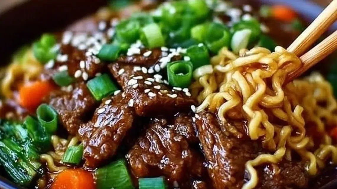 Bowl of slow cooker beef ramen noodles garnished with green onions.