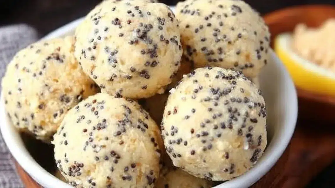 Lemon poppy seed energy bites on a wooden board with fresh lemons