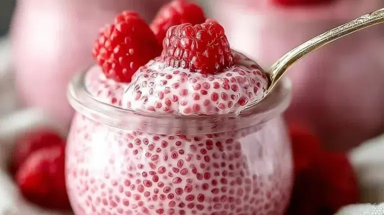 Raspberry chia pudding topped with fresh raspberries and drizzled with maple syrup