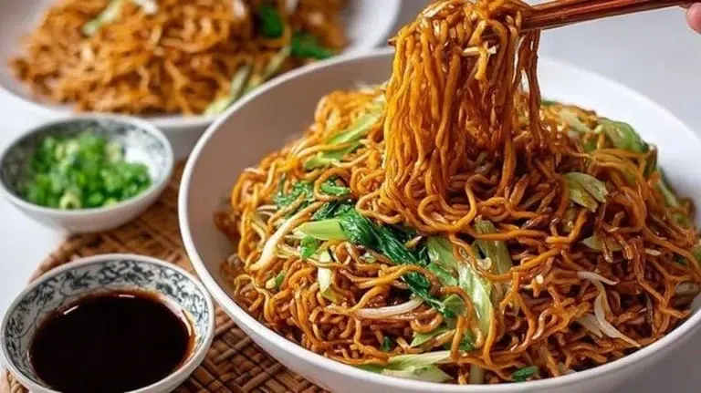 Plate of classic Chinese fried noodles garnished with vegetables and herbs