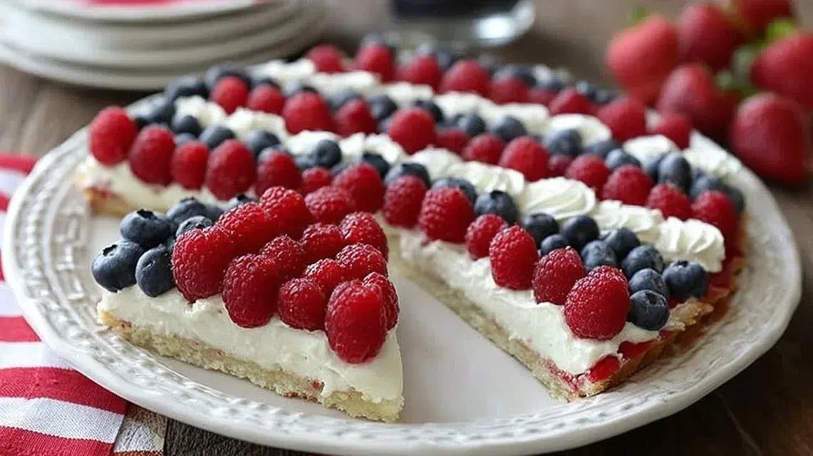 American Flag Fruit Pizza topped with strawberries and blueberries on a cookie crust