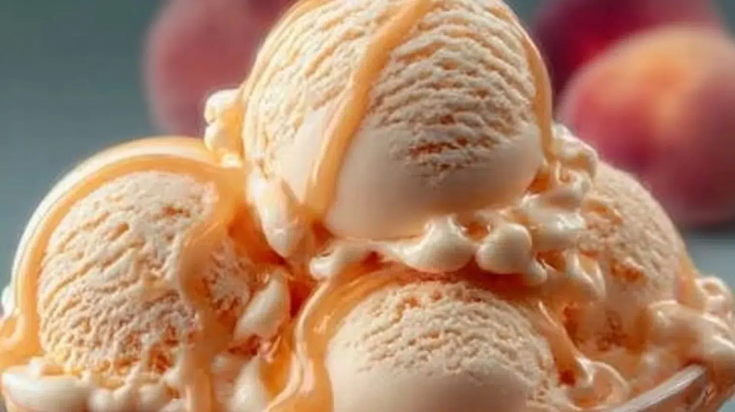 Delicious homemade peach ice cream in a bowl with fresh peaches