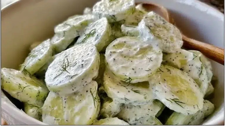 Creamy cucumber salad in a bowl with fresh herbs and cucumbers