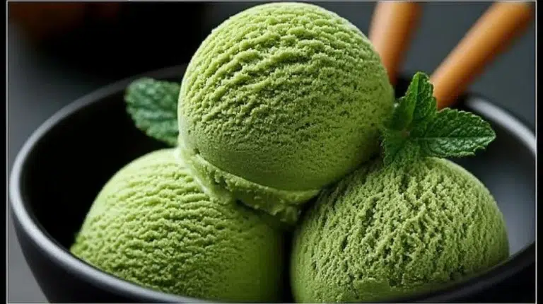 Creamy homemade matcha ice cream in a bowl with green tea leaves