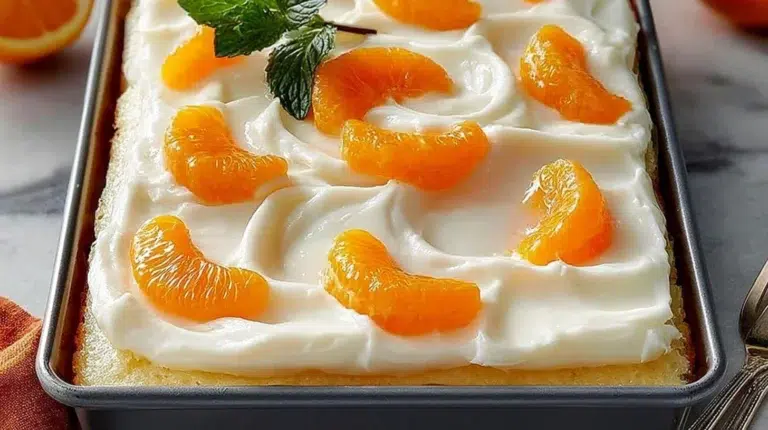 Moist Orange Jello Poke Cake decorated with whipped cream and orange slices