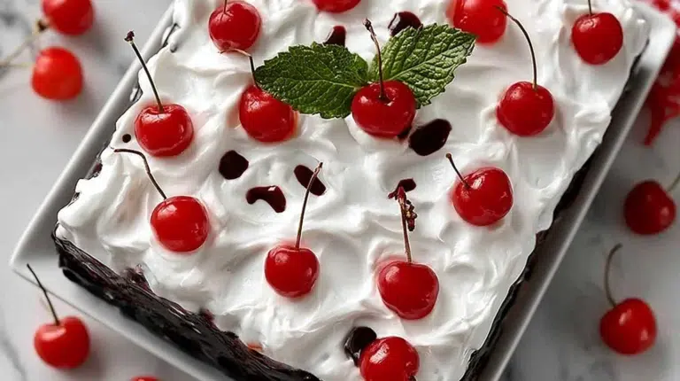 Black Forest Jello Poke Cake topped with cherries and whipped cream